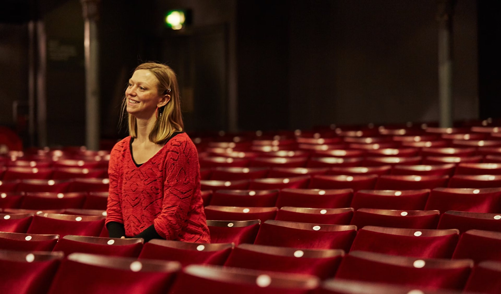 Nia Lynn sitting in the red velvet stalls of an empty theatre